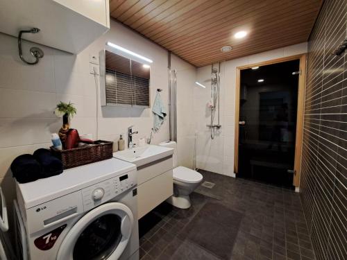 a bathroom with a washing machine and a sink at Makasiiniranta in Pori