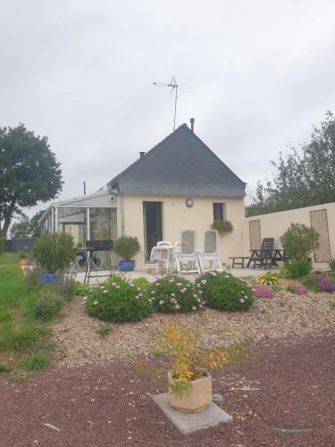 une maison dotée d'une terrasse avec des chaises et des fleurs dans l'établissement La petite maison dans la prairie, à Néant-sur-Yvel