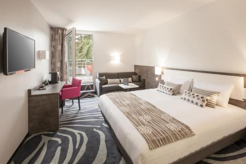 um quarto com uma cama grande e uma sala de estar em Au Comté d'Ornon Hôtel & Spa em Gradignan