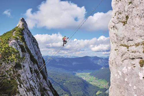 a person on a zip line on the side of a mountain at Appartements Pension Elfi in Gosau