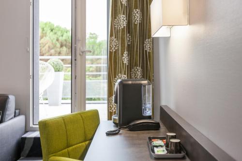 グラディニャンにあるLogis Hotel Restaurant & SPA Au Comte d'Ornonのテレビ、デスク、黄色い椅子が備わる客室です。