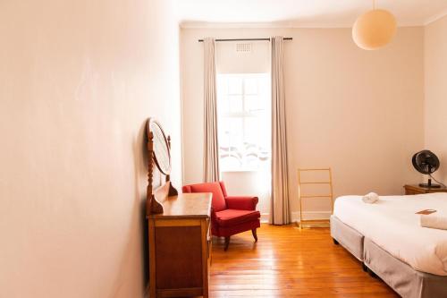 a bedroom with a red chair and a bed at Villa Viva Cape Town in Cape Town