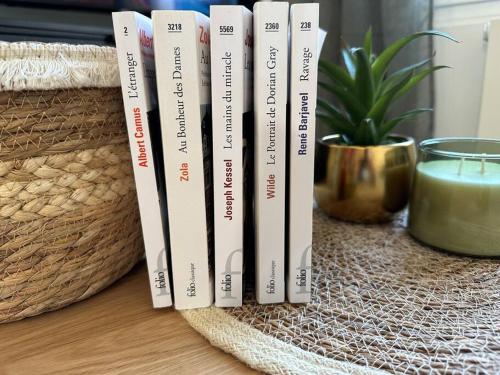 a row of books sitting on a table with a candle at « Maison Sauge » et son jardin in Deauville