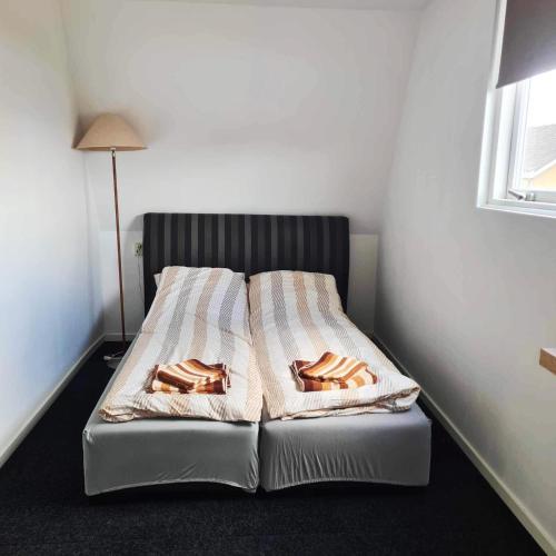 un letto in una camera con due coperte e una lampada di Horyzont a Noordwijkerhout