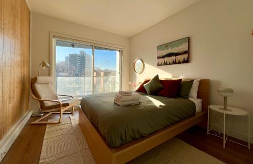 a bedroom with a bed with a chair and a window at Le Kaméleon - Lumineux et moderne, condos au centre-ville in Quebec City