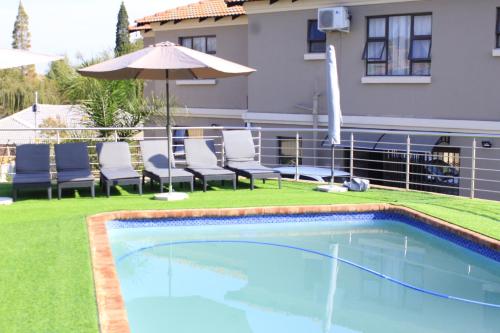 a swimming pool with chairs and an umbrella at ANGELOCEAN GUEST HOUSE in Witbank