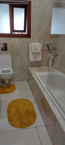 ein Badezimmer mit einer Badewanne, einem WC und einem Waschbecken in der Unterkunft LalaManzi River Lodge in Vanderbijlpark