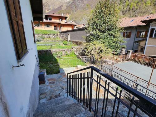een balkon met uitzicht op een huis met een trap bij Casa vacanza a Forno di Valstrona con terrazzo e giardino in Strona