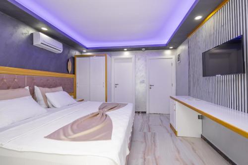 a bedroom with two beds and a tv on the wall at Cihan Bey Otel Belek in Belek