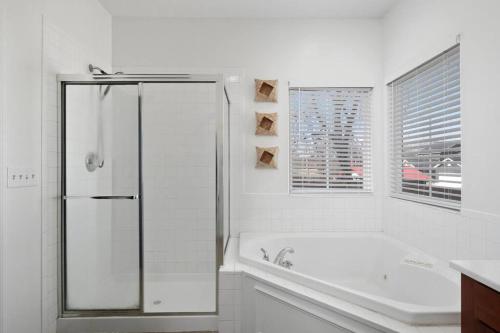 a white bathroom with a tub and a window at Modern Escape: 5BR/2.5BA Near St. Louis Must-Sees in Saint Louis