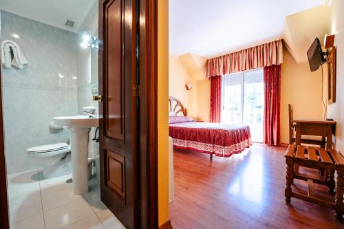 a bathroom with a bedroom with a bed and a sink at Hotel Restaurante GBC Isape in Arcade