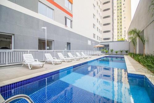uma piscina com espreguiçadeiras ao lado de um edifício em Amplo Apartamento no Brás com Piscina/Metrô Brás em São Paulo