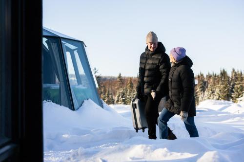 two people standing in the snow next to a truck at Nova Galaxy Village in Rovaniemi