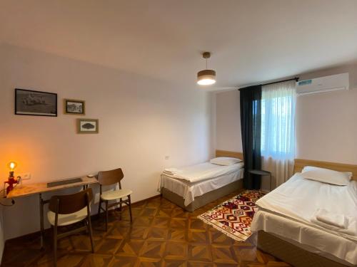 a room with two beds and a desk and a table at Crossway Camping in Yeghegnadzor
