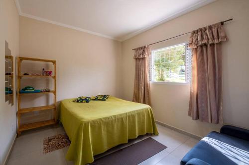 een slaapkamer met een geel bed en een raam bij Casa de Campo com lazer , pássaros e muito verde. in Poços de Caldas