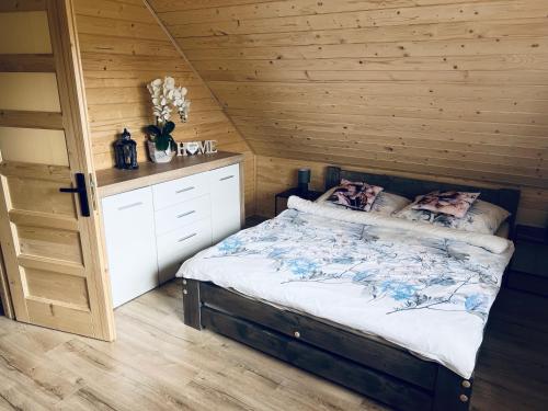 1 dormitorio con 1 cama y pared de madera en Domek RajskiRaj en Rajcza