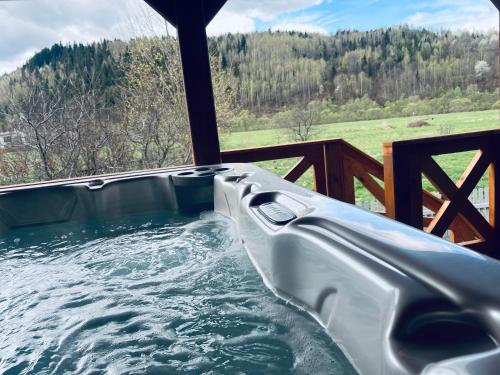 a jacuzzi tub on a porch with a view of a field at Domek RajskiRaj in Rajcza