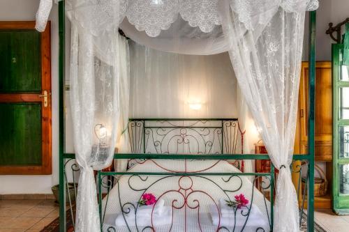 ハニア・タウンにあるIfigenia Roomsの白いカーテンとピンクの花が飾られた天蓋付きベッド