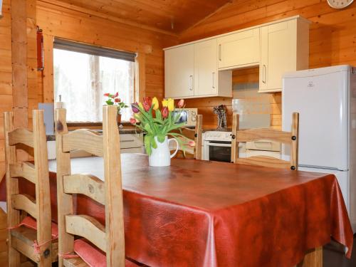 a kitchen with a table and a refrigerator at Cherry Lodge in Bodmin