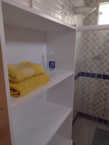 a bathroom with white shelves and a yellow towel at Casa Girassol in Itaparica