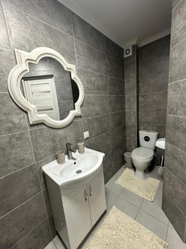 a bathroom with a sink and a mirror and a toilet at Ștefan House in Căuşeni
