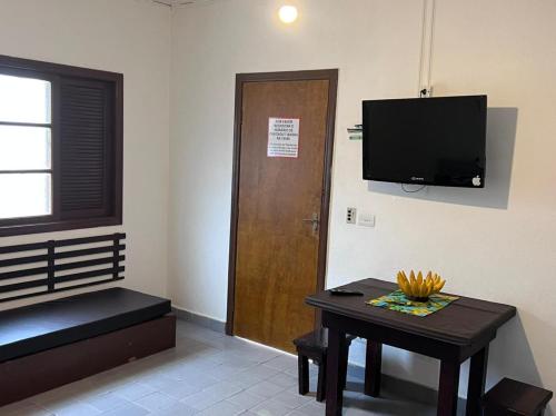 a room with a table and a television and a door at Pousada Mar Suites Toninhas in Ubatuba