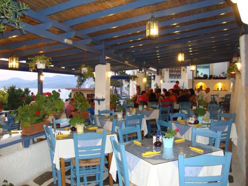 a restaurant with blue chairs and tables with people in the background at Hotel Aegean Home Studios & Apartments in Masouri
