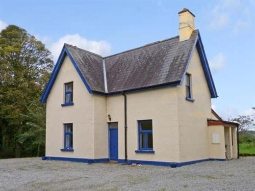 een klein wit huis met een zwart dak bij The Gardener's Cottage in Ballymote