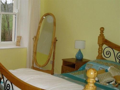 a bedroom with a wooden bed with a mirror at The Gardener's Cottage in Ballymote