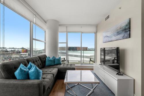 a living room with a couch and a tv at Walk to Bars, Casino, Stampede & Saddledome PLUS FREE Bonus Banff Pass, Parking & Wine! in Calgary