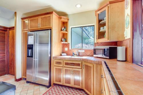 a kitchen with wooden cabinets and a stainless steel refrigerator at Enchanting Coos Bay Sanctuary with Lush Views! in Coos Bay
