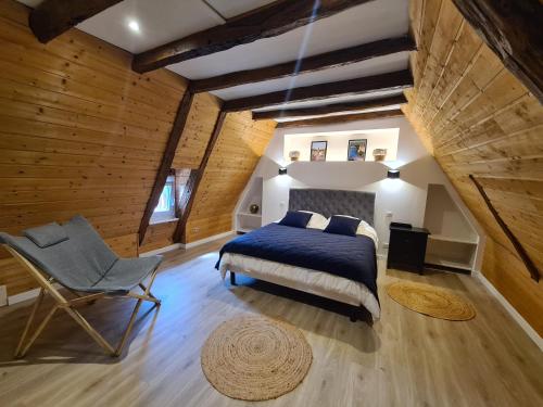 1 dormitorio con 1 cama y 1 silla en el ático en La Noz Vad, Superbe maison Perigourdine, en Saint-Cybranet
