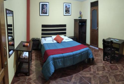 a bedroom with a bed with a blue comforter at Hospedaje Del Carmen in Machu Picchu