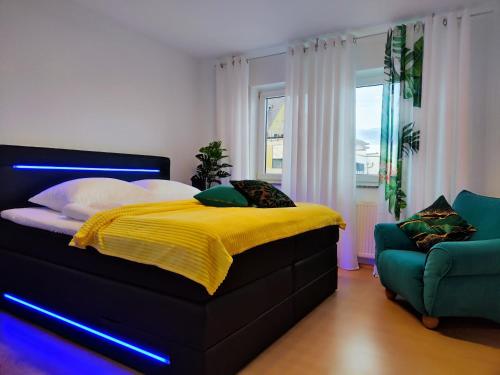 een slaapkamer met een bed met een gele deken en een stoel bij 2 Zimmer Wohnung, Küche, Bad, Balkon, Tiefgarage, Netflix in Alzey
