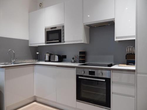 a white kitchen with white cabinets and a microwave at Apartment in Brighton in Brighton & Hove