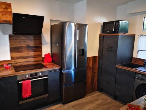 une cuisine avec des appareils électroménagers en acier inoxydable et des armoires noires dans l'établissement Cannes Cosy Oasis, à Cannes