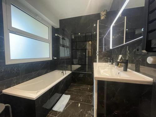 ein Badezimmer mit zwei Waschbecken, einer Badewanne und einem Fenster in der Unterkunft Cannes Cosy Oasis in Cannes