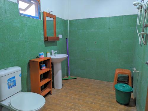 a green bathroom with a toilet and a sink at Surfpoint Sri Lanka Kite Village in Kalpitiya