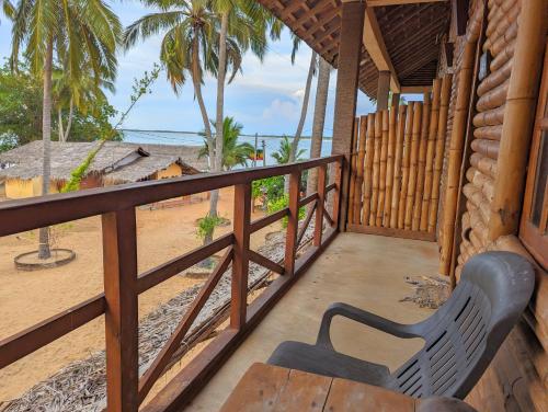 a wooden balcony with a bench on the beach at Surfpoint Sri Lanka Kite Village in Kalpitiya