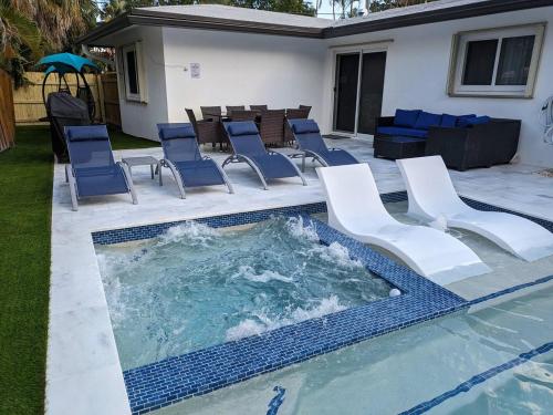 een zwembad met stoelen en een tafel bij Cozy Fun-Size Getaway + Pool&Spa 5 mins to Beach in Fort Lauderdale