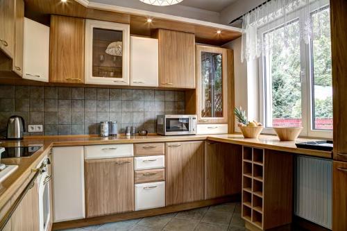 a kitchen with wooden cabinets and a microwave at Witkacówka in Zakopane