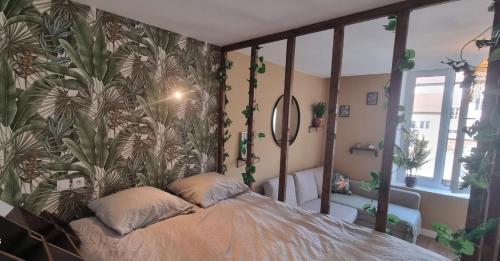 a bedroom with a bed with a tropical wallpaper at New jungle studio cœur de ville in Pont-à-Mousson