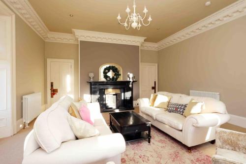 a living room with two white couches and a fireplace at Edenfield House, Springfield, Fife in Cupar