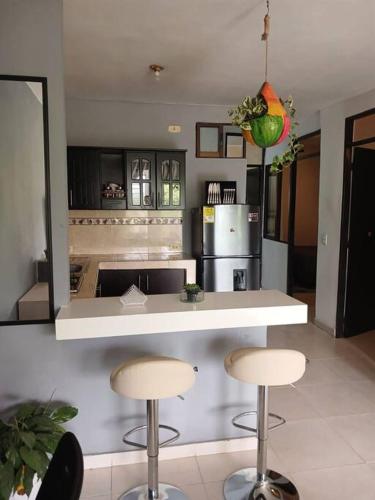 een keuken met 2 barkrukken en een aanrecht met een koelkast bij Apto 3 alcobas, Segundo piso Norte de Cali in Cali