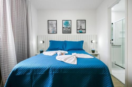 Un dormitorio con una cama azul con toallas. en Santorini Studio no Brás com Piscina/Metrô Brás, en São Paulo