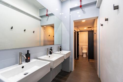 La salle de bains est pourvue de 2 lavabos et de 2 miroirs. dans l'établissement Rucksack Inn at Tyrwhitt, à Singapour