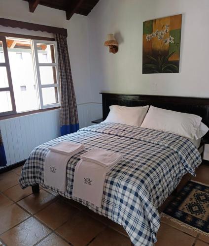 a bedroom with a bed with a checkered blanket at Cabañas Hessen - Colonia Tovar para 2 personas in El Tigre