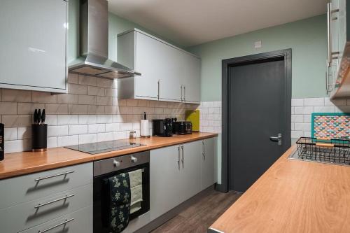 cocina con armarios blancos y encimera de madera en EDMONTON - 4 bedrooms, Sleeps 8, 3 bathroom Contractor Base, en Londres