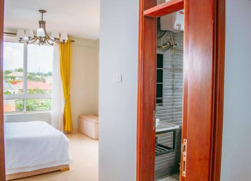 a bedroom with a bed and a bathroom with a window at Summer in Garuga in Entebbe