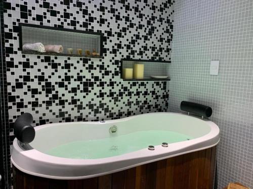 a bath tub in a bathroom with black and white tiles at Maravilhoso apartamento 2 quartos com ofurô Porto da Barra Salvador Summer Barra Flat in Salvador
